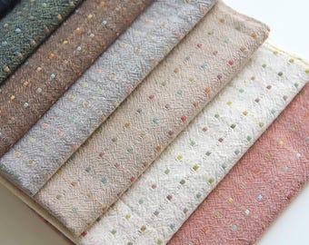 Può includere: Una pila di campioni di tessuto in vari colori, tra cui blu navy, verde, marrone, grigio, beige, bianco e rosa. Ogni campione ha un aspetto strutturato con piccoli punti colorati. Il nome "Charlene" è nell'angolo in alto a destra.