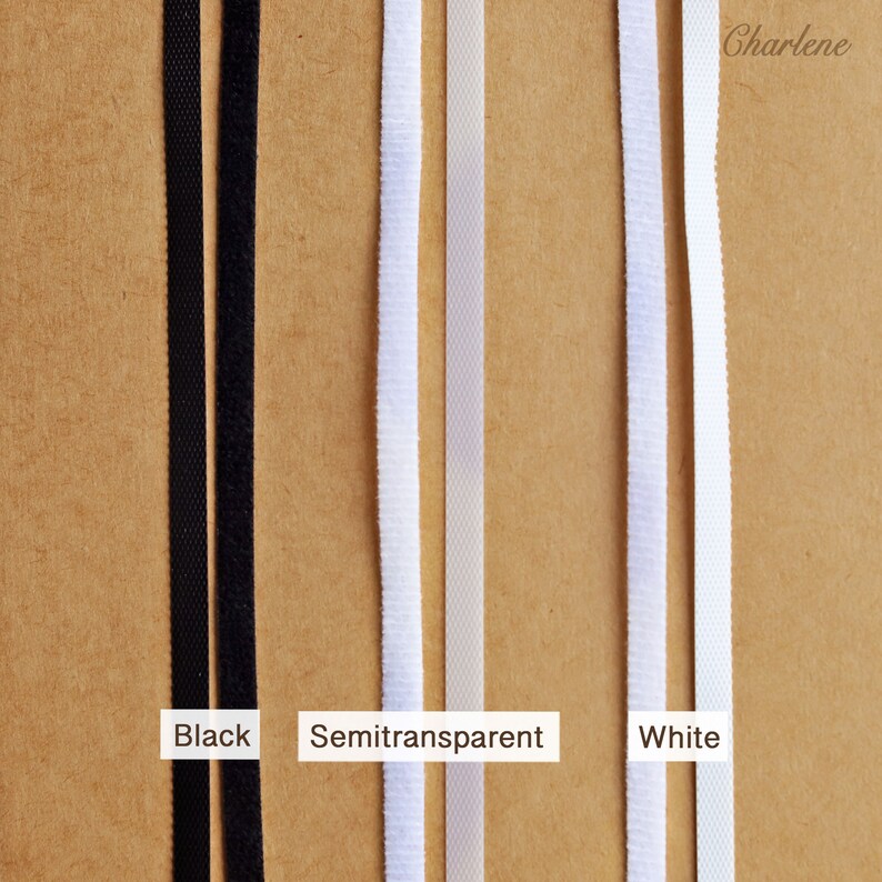 Pu&ograve; includere: Tre strisce di tessuto elastico in nero, bianco semitrasparente e bianco. Il tessuto &egrave; mostrato su uno sfondo marrone.