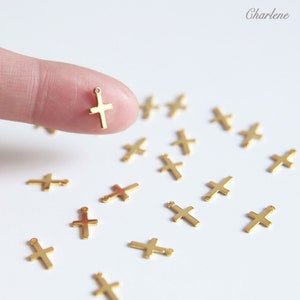 Peut inclure: Un assortiment de breloques en forme de croix en métal doré avec un trou en haut pour les attacher à des bijoux ou d'autres objets artisanaux.
