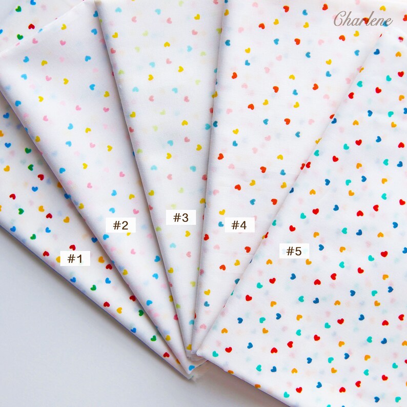 May include: Five fabric swatches with a white background and a scattered pattern of small hearts in various colours, including red, blue, yellow, pink, and green. The swatches are labelled #1 through #5.