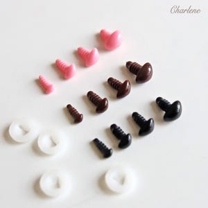 May include: Assortment of plastic safety eyes in various sizes and colors, including black, brown, and pink. The eyes are designed for use in craft projects, such as stuffed animals or dolls. There are also white plastic washers included.