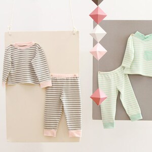 May include: Two sets of striped pajamas for children. One set is gray and white with pink trim, the other is light green and white with green trim.