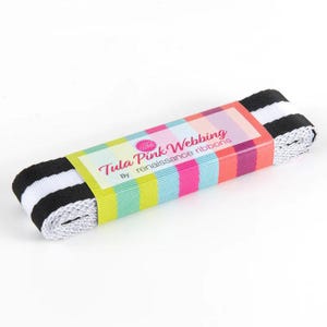 May include: A roll of black and white striped webbing ribbon with a colorful label that reads "Tula Pink Webbing" by renaissance ribbons. The label has a pink, green, blue, and orange striped pattern.