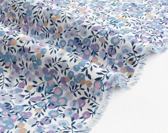 May include: White fabric with a floral pattern featuring blue, purple, pink, and tan flowers and dark blue leaves. The fabric has a frayed edge, suggesting it is cut from a larger piece. Ideal for sewing projects.