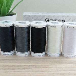 May include: Five spools of Gutermann thread in black, dark gray, light gray, off-white, and white. Each spool is labeled with the brand name and the text "100% Polyester".