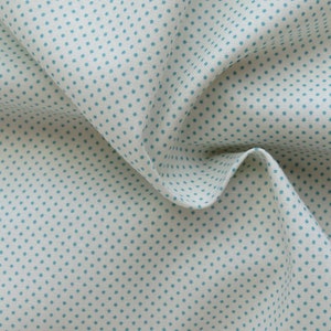 May include: Close-up of a white fabric with a repeating pattern of small, teal-colored polka dots. The fabric is folded, creating shadows and highlighting the texture of the material. The overall appearance is soft and inviting, suitable for various craft projects.