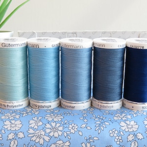 May include: Five spools of Gutermann thread in shades of blue, from light blue to dark blue. Each spool is labelled with the brand name, Gutermann, and the length of the thread in yards.