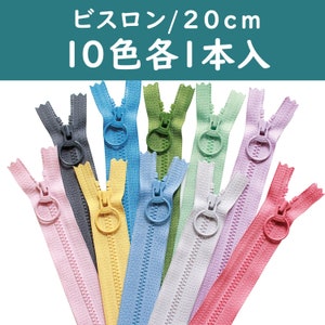 May include: A collection of ten colorful 20 cm zippers, each in a different shade, including pink, yellow, blue, and green. The zippers have a ring pull and are arranged against a white background. Text in Japanese is visible at the top.