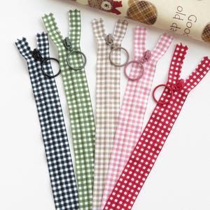 May include: Six gingham zipper pulls with different coloured gingham patterns and metal zipper pulls. The colours are black and white, green and white, brown and white, pink and white, and red and white.