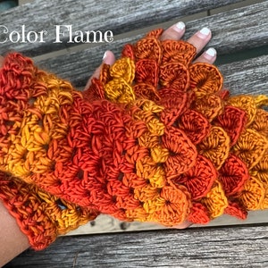 May include: Crocheted fingerless gloves in a gradient of orange, yellow, and red. The gloves are made with a textured stitch that resembles scales. The text "Color Flame" is visible in the image.