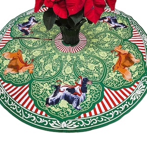 May include: A green Christmas tree skirt with a floral pattern and red and white striped border. The skirt features illustrations of birds and dogs. A poinsettia plant is in the center.
