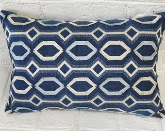 Puede incluir: Una almohada de tiro azul y blanco con un patrón geométrico y un borde con flecos.