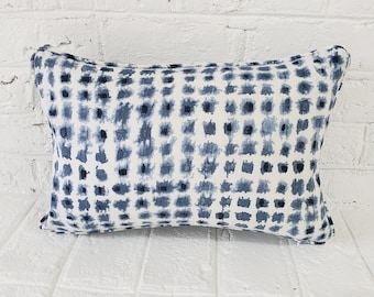 Puede incluir: Una almohada rectangular blanca y azul con un diseño geométrico. La almohada es suave y mullida.