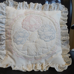 Embroidered and quilted floral basket pillow in pastel colours with ruffle