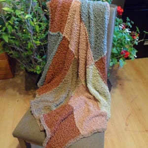 soft flowing  knitted throw constructed from earthy toned textured rectangles in mixed quality fibers