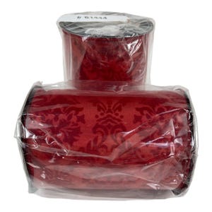Op de afbeelding: Een spoel en een rol rood damastlint, verpakt in helder plastic. Het lint heeft een donkerrood bloemmotief. De spoel staat bovenop de rol. Het label op de spoel luidt # 61444.