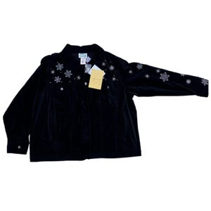 Peut inclure: Une veste en velours noir avec des embellissements en forme de flocons de neige. La veste a une fermeture à boutons et des manches longues.