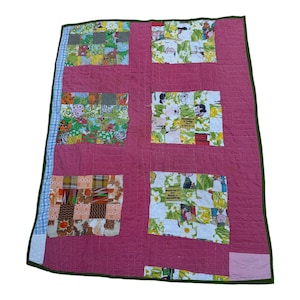 Puede incluir: Una colcha de retazos rosa con un borde verde. La colcha está hecha de cuadrados de diferentes telas, incluyendo estampados florales, personajes de dibujos animados y patrones a cuadros. El texto "Happiness is holding on to the good times" es visible en uno de los cuadrados.