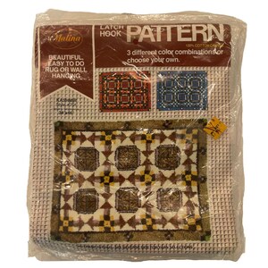 May include: A packaged latch hook rug pattern kit. The kit includes a rug pattern with a geometric design in shades of brown, beige, and yellow. The packaging includes the text "Beautiful, Easy to Do Rug or Wall Hanging."