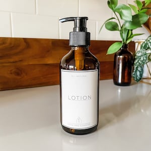 May include: A brown glass bottle with a black pump dispenser filled with lotion. The bottle has a white label that reads "All Natural Lotion" and "toxin free cleaning".