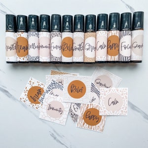May include: A set of 14 essential oil roller bottles with labels featuring various animal print designs and text such as "Breathe", "Wellbeing", "Energy", "Relief", "Soothe", "Stress", "Calm", "Happy", "Focus", and "Seasonal".