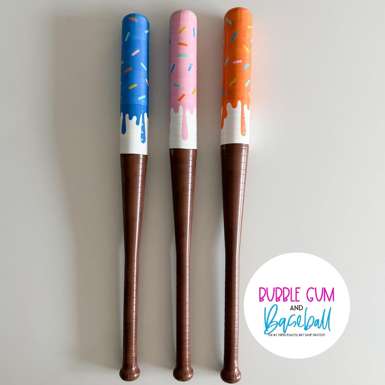 May include: Three baseball bats with a unique ice cream cone design. Each bat features a different color scheme: blue with sprinkles, pink with sprinkles, and orange with sprinkles. The handles are brown, and the tops have a white drip effect.