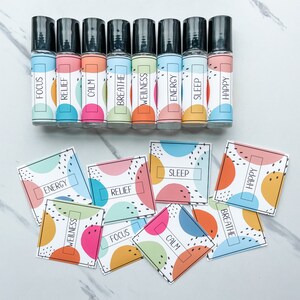 以下が含まれることがあります： さまざまなエッセンシャルオイルブレンドのラベルが付いた、カラフルなローラーボトルが10本。ラベルには、Focus、Relief、Calm、Breathe、Wellness、Energy、Sleep、Happyと記載されています。同じ言葉とカラフルな円のデザインが描かれた正方形のラベルも8枚あります。