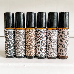 May include: Six amber glass roller bottles with black caps and leopard print labels. The labels are in shades of brown, black, and white.