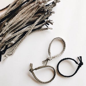 May include: A set of three braided leather bracelets in black and gray. The bracelets are made of a soft, supple leather and are perfect for everyday wear.