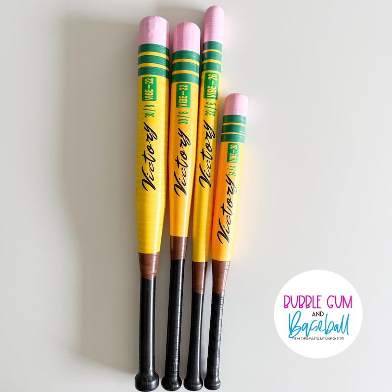 May include: Four yellow baseball bats with pink ends, green and yellow stripes, and black handles. The bats have the word "Victory" in cursive and the text "30/8 VIBE-22", "32/5 VIBE-26", and "N/4 VIBE-20".