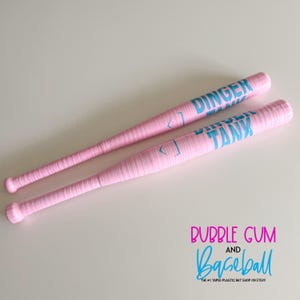 May include: Two pink baseball bats with blue text that reads "DINGER TANK". The bats are wrapped in a textured material. The image also includes the text "BUBBLE GUM and Baseball".