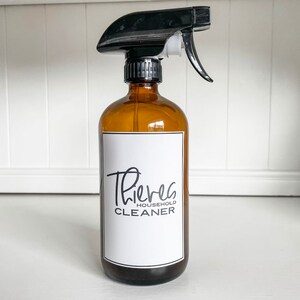 May include: A brown glass spray bottle with a black trigger sprayer. The bottle has a white label with the text "Thieves Household Cleaner".