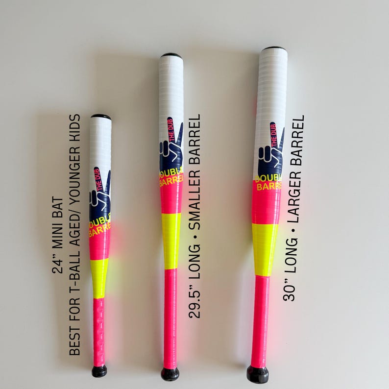 May include: Three baseball bats in white, neon pink, and yellow. Each bat features the text "THE DUB DOUBLE BARREL" and a peace sign graphic. The bats are 61 cm, 75 cm, and 76 cm long, suitable for different age groups.