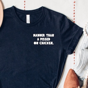 May include: Black t-shirt with white text that reads "Madder than a pissed on chicken."