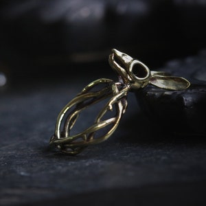 May include: A gold-toned ring featuring a detailed rabbit skull design with intricate branch-like details around the band.