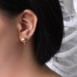 May include: Gold skull stud earrings. The earrings are small and delicate, and they are perfect for adding a touch of edgy style to any outfit.