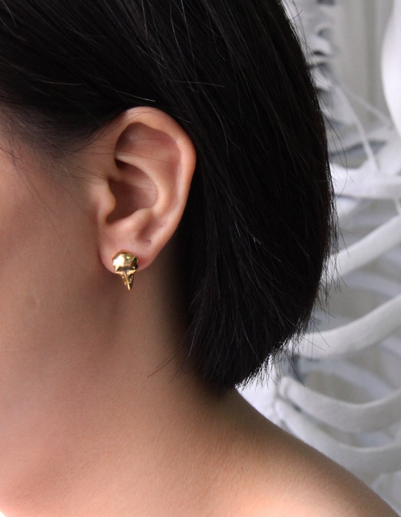 May include: Gold skull stud earrings. The earrings are small and delicate, and they are perfect for adding a touch of edgy style to any outfit.