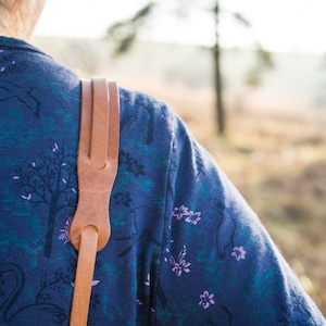 Peut inclure: Une personne portant une chemise bleue à motif floral et une sangle en cuir marron sur l'épaule.