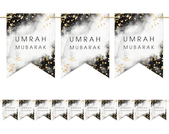 May include: Black and white banner with gold glitter accents. The banner has the text "UMRAH MUBARAK" repeated on each flag.