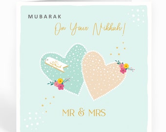 May include: A light blue card with two intertwined hearts, one light blue and one peach, with white polka dots. The hearts have gold outlines and are decorated with white pearls. The card has the text "MUBARAK On Your Nikkah!" in gold lettering and "MR & MRS" in gold lettering at the bottom. The card has a light blue background with white polka dots and gold stars.