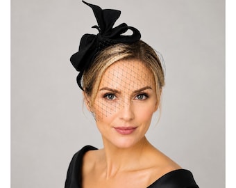 Elegant svart filtfascinator med fågelburslöja och skulptural rosett