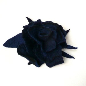 K&ouml;nnte beinhalten: Eine dunkelblaue Filzblume, die einer Rose &auml;hnelt, mit gekr&auml;uselten und strukturierten Bl&uuml;tenbl&auml;ttern. Die Blume ist aus Wollfilz gefertigt und hat ein nat&uuml;rliches, handgemachtes Aussehen.