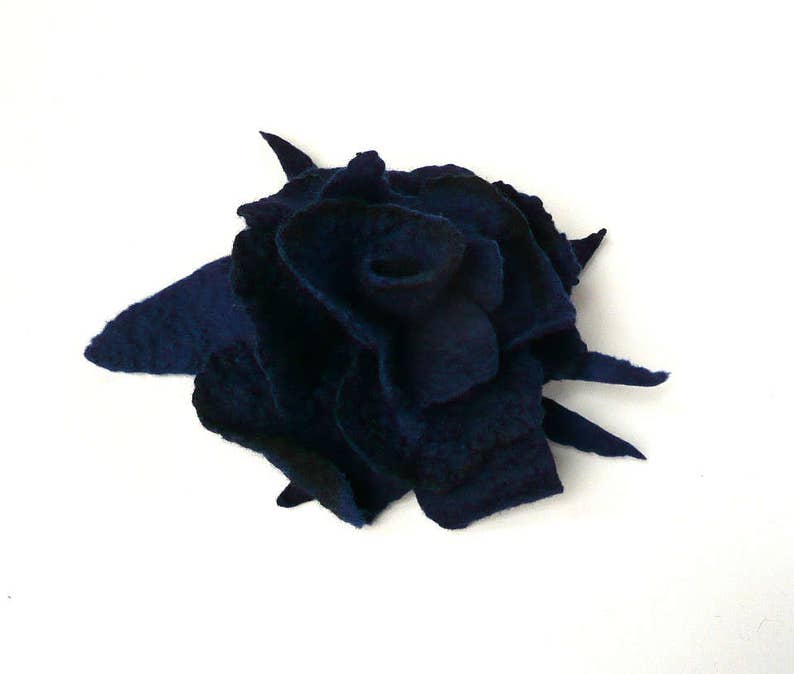 K&ouml;nnte beinhalten: Eine dunkelblaue Filzblume, die einer Rose &auml;hnelt, mit gekr&auml;uselten und strukturierten Bl&uuml;tenbl&auml;ttern. Die Blume ist aus Wollfilz gefertigt und hat ein nat&uuml;rliches, handgemachtes Aussehen.