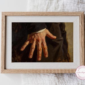 May include: A framed art print showing a detailed painting of a hand with visible skin texture and shadows. The hand is reaching out, with the fingers slightly spread. The artwork is set in a light wood frame.