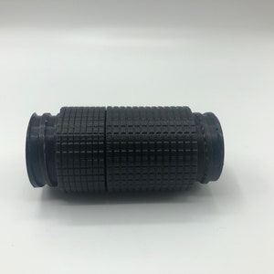 May include: A black, cylindrical object with a textured, grid-like pattern. The object appears to be made of plastic or a similar material. It has a series of ridges and grooves at each end, and is approximately 6 inches long.