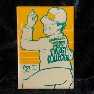 Könnte beinhalten: Eine gelbe und weiße Comic-Illustration eines Sanitärarbeiters, der einen grünen Hut trägt und ein grünes Schild mit der Aufschrift "Garbageman Sanitation Engineer Energy Collector" hält. Das Schild befindet sich auf einem gelben Hintergrund mit weißem Rand. Das Bild enthält auch das Logo des Ministeriums für Energie Ontario.
