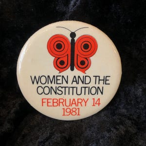 Könnte beinhalten: Ein weißer Knopf mit einem roten Schmetterlingsdesign und dem Text "Women and the Constitution" und "February 14, 1981".