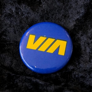 May include: A blue and yellow button with the word "VIA" in yellow letters.