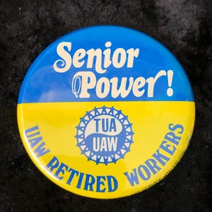 May include: A yellow and blue button with the text "Senior Power!" and "UAW Retired Workers" around a blue circle with the text "TUA UAW".