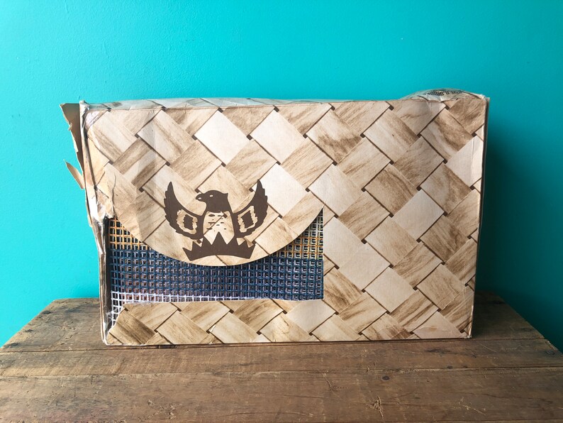 May include: A brown cardboard box with a woven pattern and a brown eagle logo. The box has a blue mesh window.